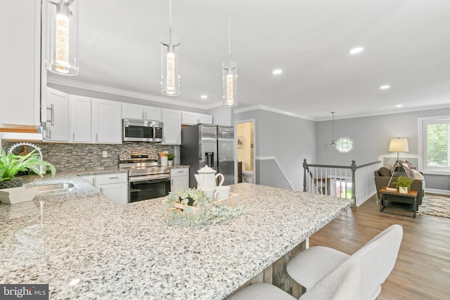 7102 Walnut Ave, Baltimore, MD 21208 - kitchen featuring stainless steel appliances, light wood-style floors, crown molding, light stone countertops, and backsplash