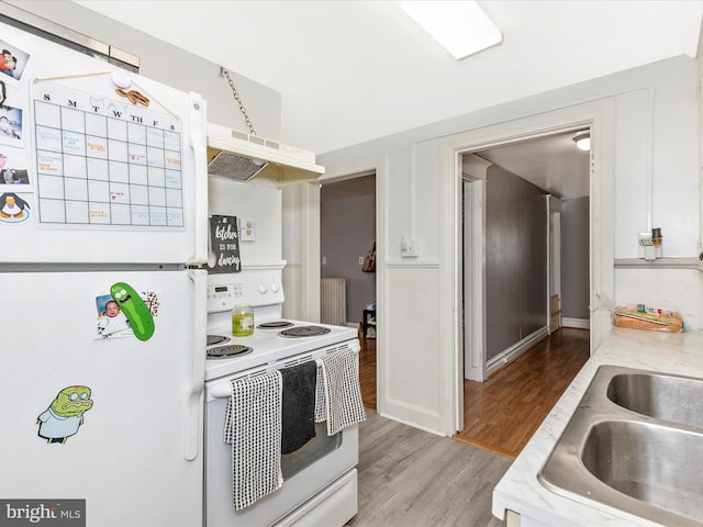 250 E E Main St, Waynesboro, PA 17268 - kitchen with white appliances, under cabinet range hood, light countertops, radiator, and light wood finished floors