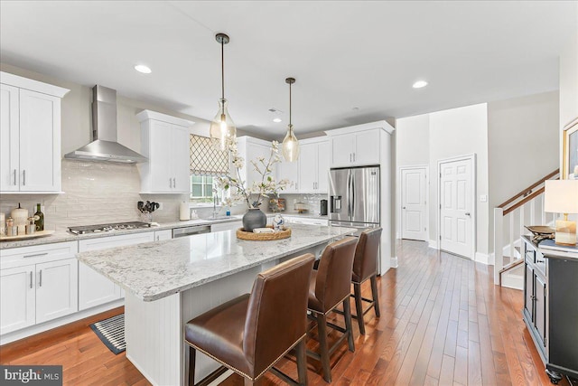 1009 James Walter Way, Kennett Square, PA 19348 - kitchen featuring wall chimney range hood, appliances with stainless steel finishes, a kitchen breakfast bar, white cabinets, and decorative backsplash