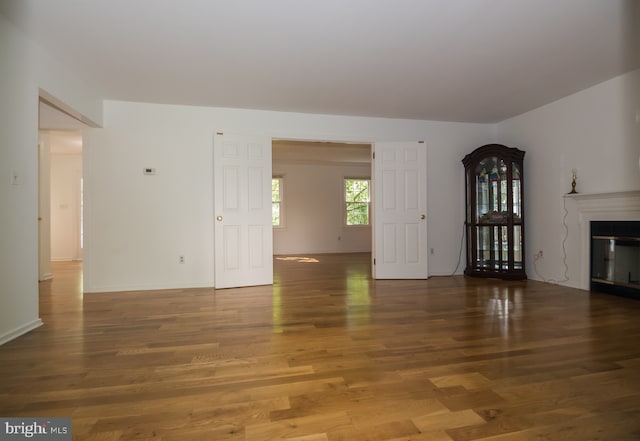 9 Paddington Ct, Hockessin, DE 19707 - unfurnished living room featuring wood finished floors, a glass covered fireplace, and baseboards