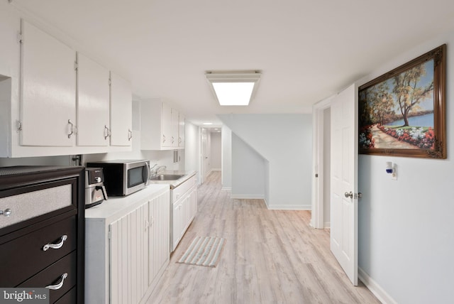 7434 Dickenson St, Springfield, VA 22150 - kitchen with white cabinetry, light wood-style floors, stainless steel microwave, a sink, and light countertops