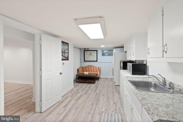 7434 Dickenson St, Springfield, VA 22150 - kitchen with stainless steel microwave, a sink, white cabinets, light wood finished floors, and baseboards