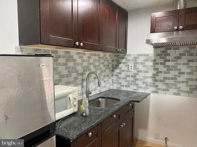 2600 S Mildred St, Philadelphia, PA 19148 - kitchen with freestanding refrigerator, white microwave, a sink, extractor fan, and dark stone countertops