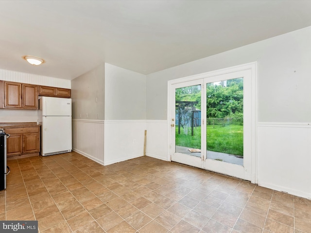 7324 E Springbrook Ct, Middletown, MD 21769 - kitchen featuring freestanding refrigerator, wainscoting, brown cabinetry, stove, and stone finish floors