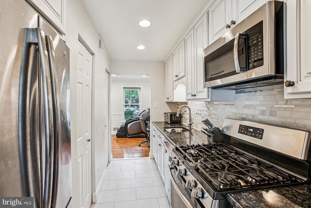 11910 Saint Johnsbury Ct, Reston, VA 20191 - kitchen featuring appliances with stainless steel finishes, light tile patterned flooring, backsplash, a sink, and white cabinetry