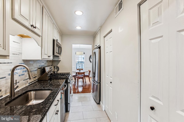 11910 Saint Johnsbury Ct, Reston, VA 20191 - kitchen with appliances with stainless steel finishes, a sink, backsplash, light tile patterned floors, and dark stone countertops