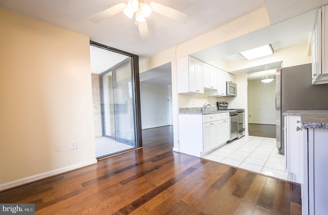 4500 Four Mile Run Dr Unit 211, Arlington, VA 22204 - kitchen featuring stainless steel appliances, light wood finished floors, white cabinetry, a ceiling fan, and light stone counters