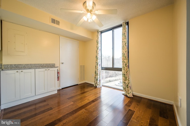 4500 Four Mile Run Dr Unit 211, Arlington, VA 22204 - spare room with a textured ceiling, a ceiling fan, baseboards, a wall of windows, and dark wood-style flooring