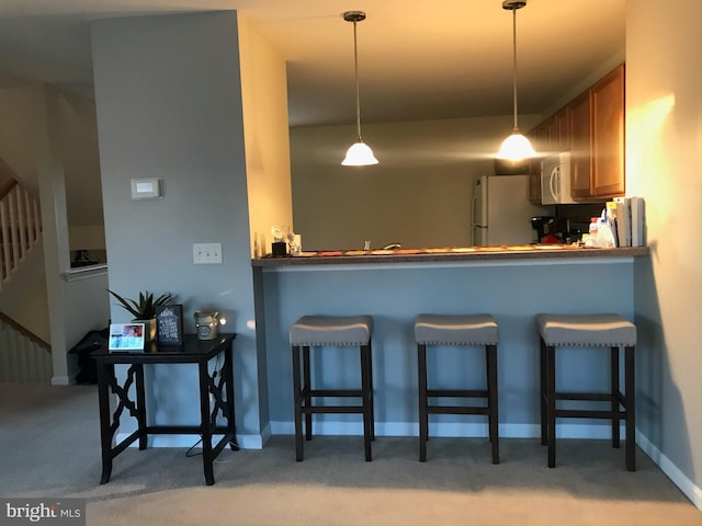115 E Sheldrake Cir, Dover, DE 19904 - kitchen with white appliances, light carpet, brown cabinetry, and pendant lighting