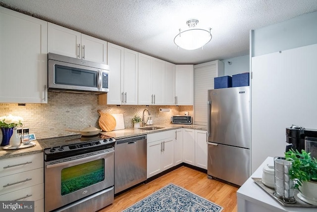 1600 N Oak St Unit 324, Arlington, VA 22209 - kitchen featuring stainless steel appliances, a sink, white cabinets, light wood-type flooring, and decorative backsplash