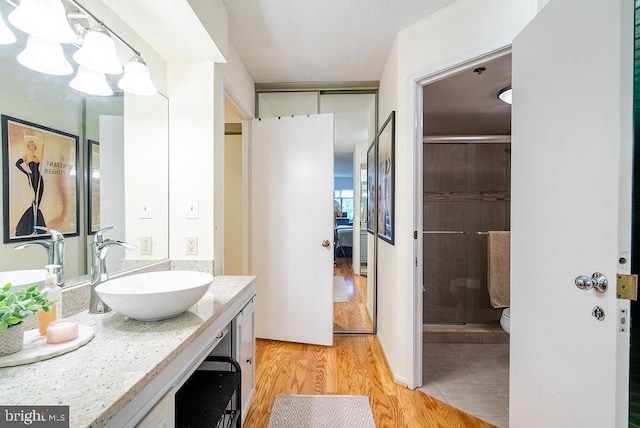 1600 N Oak St Unit 324, Arlington, VA 22209 - full bathroom featuring vanity, an enclosed shower, wood finished floors, toilet, and a chandelier