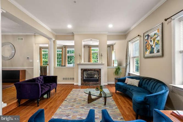 living room with wood finished floors, crown molding, a glass covered fireplace, recessed lighting, and baseboards