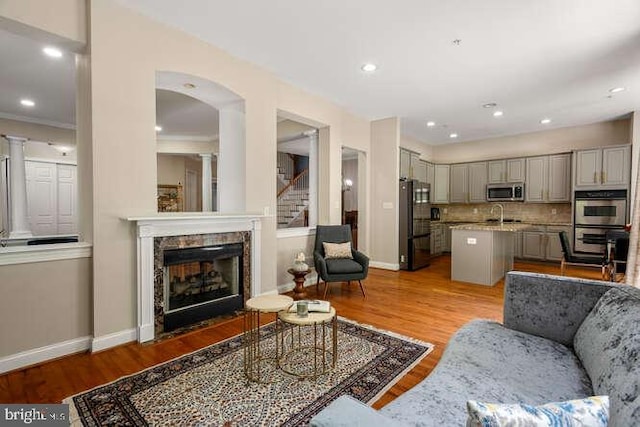 living area featuring baseboards, light wood-type flooring, stairs, and recessed lighting