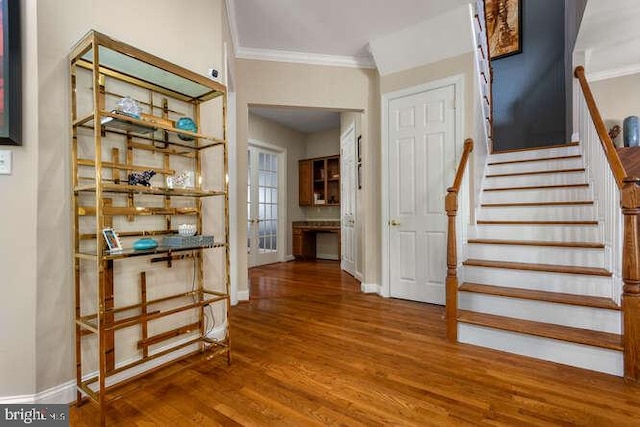 foyer with ornamental molding, wood finished floors, stairway, and baseboards