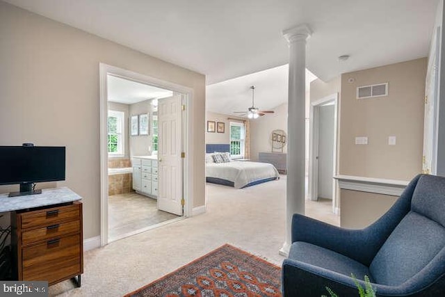 bedroom featuring light colored carpet, baseboards, ornate columns, ensuite bathroom, and ceiling fan