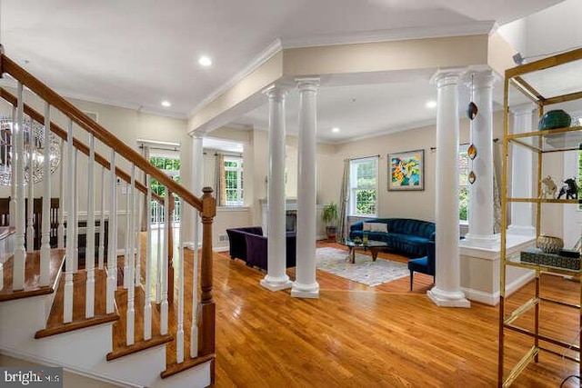 stairs featuring decorative columns, crown molding, wood finished floors, and recessed lighting