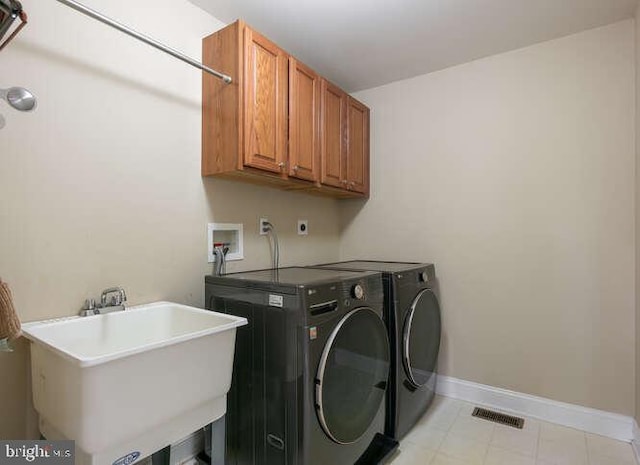 laundry area featuring cabinet space, washer and dryer, baseboards, and light tile patterned floors
