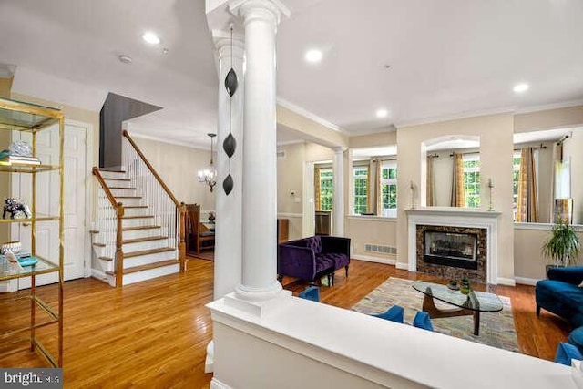 living area featuring decorative columns, crown molding, wood finished floors, stairway, and recessed lighting
