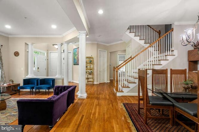 living room featuring decorative columns, wood finished floors, stairway, ornamental molding, and baseboards