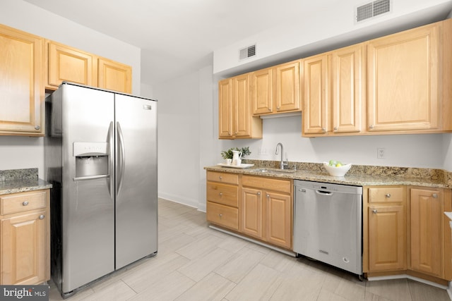 704 F St NE, Washington, DC 20002 - kitchen with appliances with stainless steel finishes, light brown cabinetry, a sink, light stone counters, and baseboards