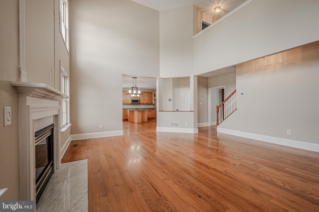 143 Bakerfield Dr, Middletown, DE 19709 - unfurnished living room with a fireplace, a high ceiling, light wood-style floors, stairway, and a chandelier