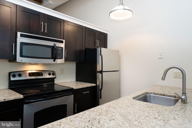 2429 Locust St Unit 319, Philadelphia, PA 19103 - kitchen with stainless steel appliances, a sink, dark brown cabinetry, and light stone countertops