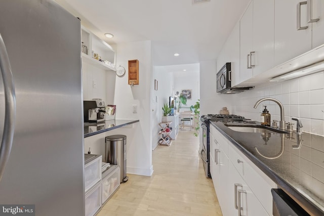 961 Randolph St NW Unit 3, Washington, DC 20011 - kitchen featuring appliances with stainless steel finishes, a sink, decorative backsplash, white cabinets, and light wood-style flooring