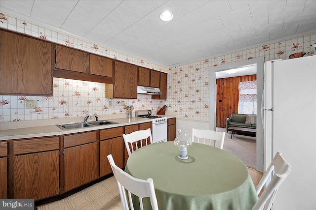 104 11th St, Ocean City, MD 21842 - kitchen with white appliances, under cabinet range hood, a sink, wallpapered walls, and light countertops
