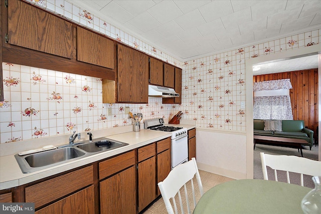 104 11th St, Ocean City, MD 21842 - kitchen featuring white gas range oven, under cabinet range hood, a sink, light countertops, and wallpapered walls