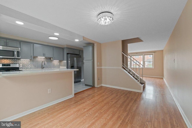 911 Circle Dr, Baltimore, MD 21227 - kitchen featuring appliances with stainless steel finishes, light wood-style floors, gray cabinets, light countertops, and decorative backsplash