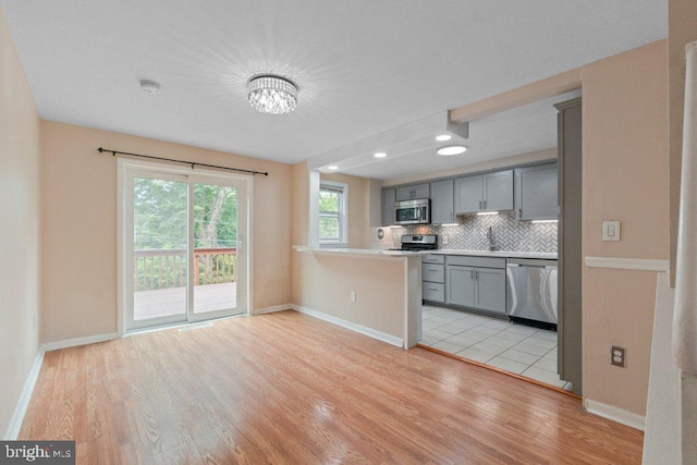911 Circle Dr, Baltimore, MD 21227 - kitchen featuring appliances with stainless steel finishes, gray cabinetry, light wood-style flooring, decorative backsplash, and recessed lighting