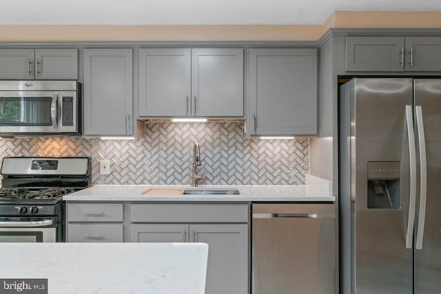 911 Circle Dr, Baltimore, MD 21227 - kitchen featuring appliances with stainless steel finishes, gray cabinetry, a sink, light countertops, and decorative backsplash