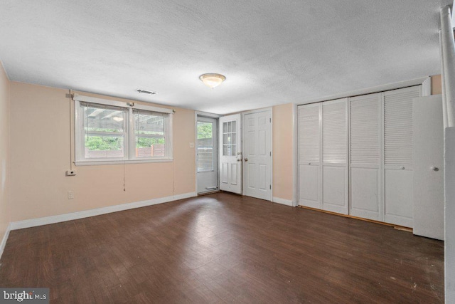 911 Circle Dr, Baltimore, MD 21227 - unfurnished bedroom featuring a textured ceiling, wood finished floors, baseboards, and multiple closets