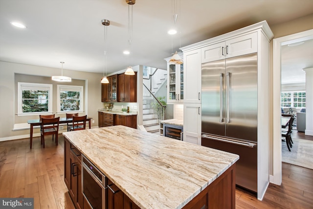 2371 N Edgewood St, Arlington, VA 22207 - kitchen with built in appliances, glass insert cabinets, light wood finished floors, white cabinetry, and light stone counters