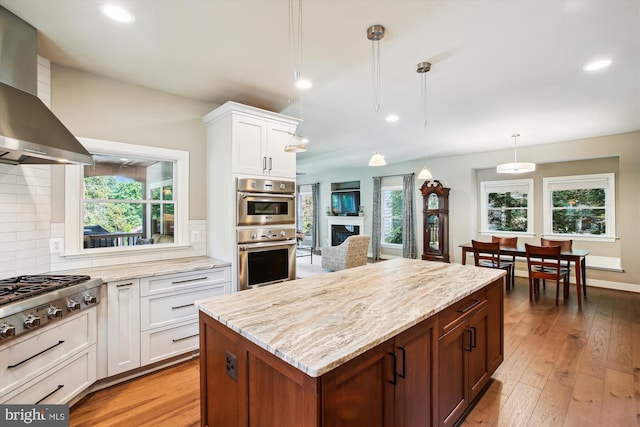 2371 N Edgewood St, Arlington, VA 22207 - kitchen featuring wall chimney exhaust hood, stainless steel appliances, decorative backsplash, white cabinets, and light stone counters