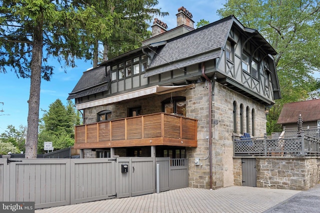 1202 W Wynnewood Rd Unit 1, Wynnewood, PA 19096 - view of front of house with stone siding, a shingled roof, a balcony, and a chimney