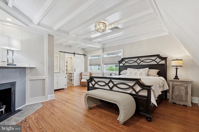 1202 W Wynnewood Rd Unit 1, Wynnewood, PA 19096 - bedroom with a barn door, wood finished floors, beamed ceiling, baseboards, and a fireplace with flush hearth