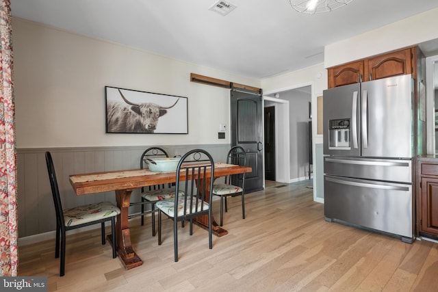 105 Stonewyck Dr, Lancaster, PA 17603 - dining area with light wood finished floors, a barn door, and a wainscoted wall