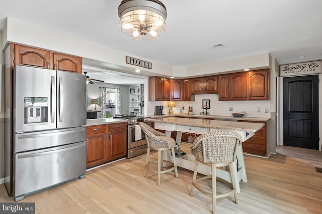 105 Stonewyck Dr, Lancaster, PA 17603 - kitchen with stainless steel appliances, brown cabinets, light wood-style flooring, and tasteful backsplash