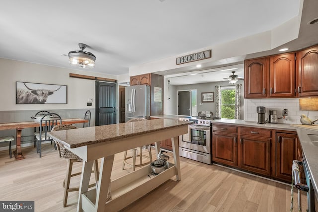 105 Stonewyck Dr, Lancaster, PA 17603 - kitchen featuring stainless steel appliances, a barn door, light wood finished floors, ceiling fan, and a wainscoted wall