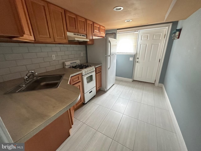 8854 Calvert St, Philadelphia, PA 19152 - kitchen with white range with gas cooktop, a sink, under cabinet range hood, brown cabinets, and decorative backsplash