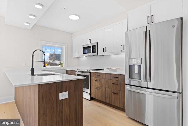 919 12th St NE Unit 201, Washington, DC 20002 - kitchen featuring appliances with stainless steel finishes, a sink, light wood-style floors, and white cabinetry