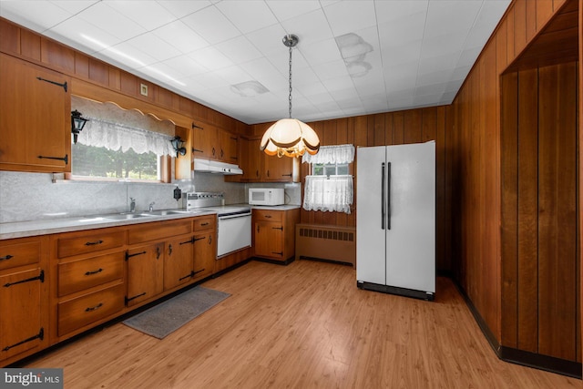 2138 Hill Rd, Perkiomenville, PA 18074 - kitchen featuring white appliances, under cabinet range hood, radiator heating unit, brown cabinets, and wooden walls