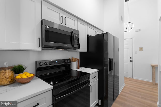 1490 Greenbriar Cir Unit 1-1490, Pikesville, MD 21208 - kitchen featuring black appliances, light wood-style flooring, white cabinetry, light stone countertops, and baseboards