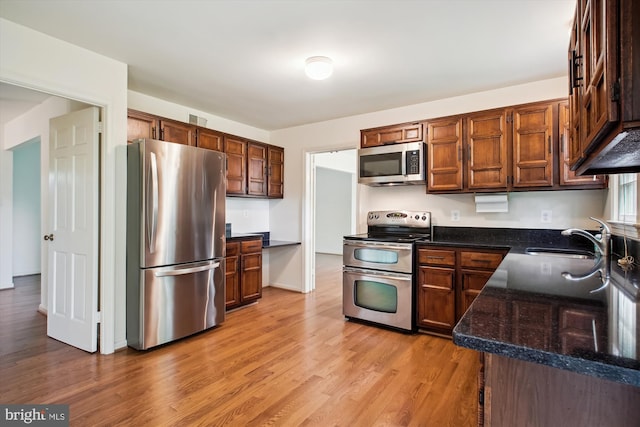 1881 Cold Creek Ct, Vienna, VA 22182 - kitchen featuring stainless steel appliances, a sink, light wood-style floors, and dark stone counters