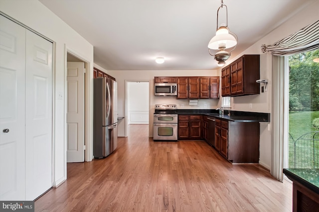 1881 Cold Creek Ct, Vienna, VA 22182 - kitchen featuring stainless steel appliances, dark countertops, light wood-type flooring, and decorative light fixtures