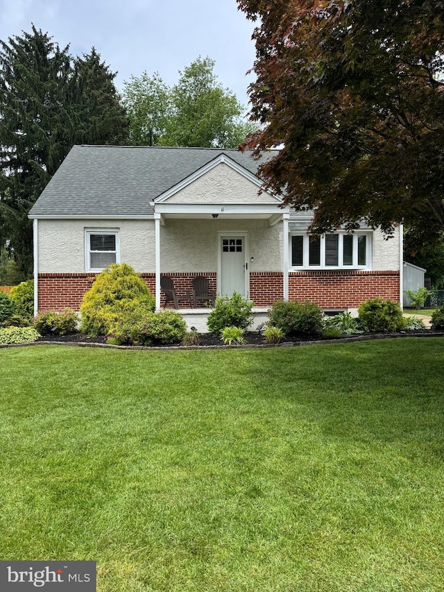 618 Ruth, Upper Chichester, PA 19014 - view of front facade featuring brick siding, a front yard, a shingled roof, and stucco siding