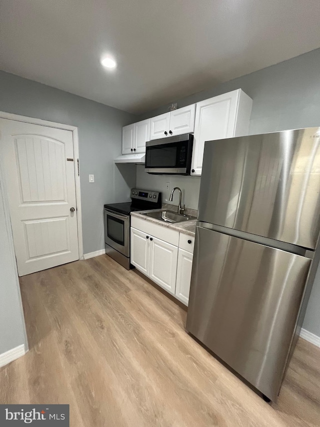 1500 Centre Ave, Reading, PA 19601 - kitchen with appliances with stainless steel finishes, baseboards, a sink, white cabinets, and light wood-style flooring