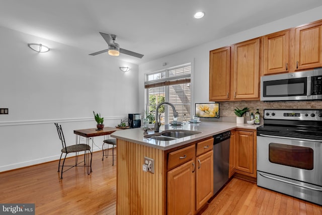 620 Cypress Ln, Severna Park, MD 21146 - kitchen with appliances with stainless steel finishes, light wood-style floors, ceiling fan, decorative backsplash, and light countertops