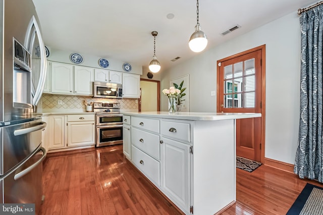 665 Bayard Rd, Lothian, MD 20711 - kitchen featuring appliances with stainless steel finishes, dark wood-type flooring, light countertops, a kitchen island, and tasteful backsplash